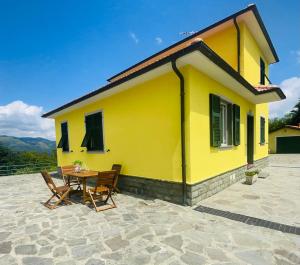 a yellow house with a table and chairs at Colle del Faggio Nature Home in Cassego