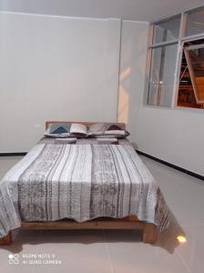 a bedroom with a bed with a striped comforter at Casa Alojamiento Virreynal in San Ramón