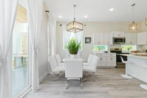 een witte keuken met een tafel en witte stoelen bij Davis Shores Lookout- Dog Friendly Mins to DNTN & Beach in St. Augustine