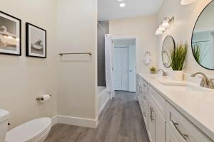 een witte badkamer met 2 wastafels en een toilet bij Davis Shores Lookout- Dog Friendly Mins to DNTN & Beach in St. Augustine