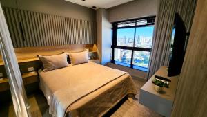 a bedroom with a bed and a tv and a window at Luxury Collection By Vertigo 23º Floor in Campo Grande +12 photos