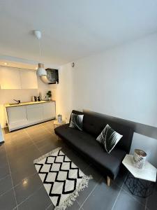 salon z czarną kanapą i kuchnią w obiekcie Le Central : Appartement cosy et calme w mieście Saint-Germain-de-Joux