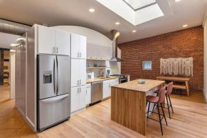 eine Küche mit einem großen Kühlschrank und einem Holztisch in der Unterkunft Deluxe 3BR Loft Walkable to Everything Downtown in Cincinnati