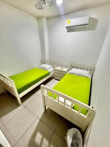 two beds in a room with green sheets at Hostal Lumar in Barranquilla