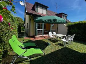 eine Terrasse mit einem Tisch, Stühlen und einem Sonnenschirm in der Unterkunft Noémi nyaralóház in Bük