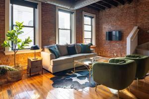 a living room with a couch and a brick wall at Stunning Loft in the heart of OTR in Cincinnati