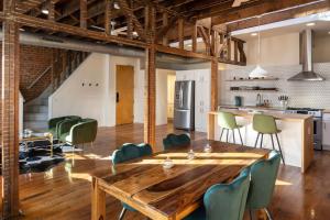 Stunning Loft in the heart of OTR في سينسيناتي: مطبخ مفتوح وغرفة طعام مع طاولة وكراسي خشبية
