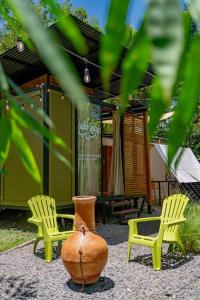 zwei Stühle, eine Vase und zwei Stühle in einem Hof in der Unterkunft Tiny garden house in Turrialba