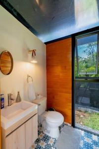 La salle de bains est pourvue de toilettes, d'un lavabo et d'une fenêtre. dans l'établissement Tiny garden house, à Turrialba