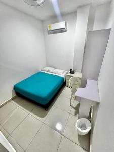a small room with a blue bed and a desk at Hostal Lumar in Barranquilla