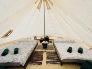 two beds in a tent with a table at WINE ROAD GLAMPING in Cuvin