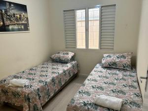 um quarto com 2 camas e uma janela em Casa incrível com 2 quartos e estacionamento incluso em Maringá