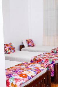 um quarto com 2 camas com almofadas florais em Hotel Sanasuma em Hambantota