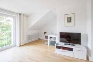 Traum-Ferienwohnung Alpenblick في باد ايبلنغ: غرفة معيشة بيضاء مع تلفزيون ومكتب