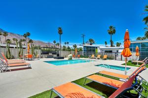 a swimming pool with lawn chairs and umbrellas at Stunning Palm Springs 2 Bedroom Condo in Palm Springs
