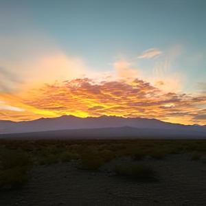 una puesta de sol en el desierto con montañas en el fondo en cabañas de montaña en Uspallata
