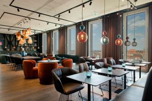 a restaurant with tables and chairs and windows at The Cloud One Nürnberg, by the Motel One Group in Nürnberg