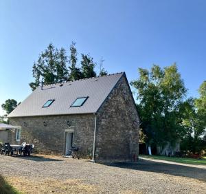 une grange en pierre avec des lucarnes au-dessus de celle-ci dans l'établissement Bien être à la campagne, à Le Mesnil-Amand