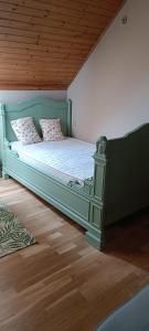 una camera da letto con letto verde e cuscini rosa di Les roses d'Olga 