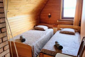 two twin beds in a room with wooden walls at Viesu māja Kolnā pie Adamovas ezera. 