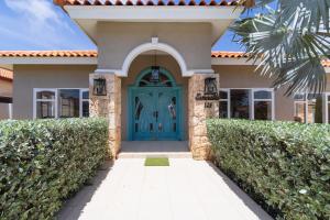 uma casa com uma porta azul e alguns arbustos em Esmeralda 126 em Palm Beach