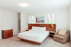 een slaapkamer met een wit bed en een stoel bij Skaneateles Suites Boutique Hotel in Skaneateles