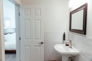 een witte badkamer met een wastafel en een spiegel bij Skaneateles Suites Boutique Hotel in Skaneateles