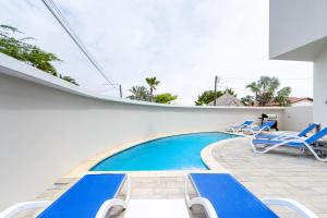 una piscina en una casa con tumbonas azules en Summerside 4 Rooi Santo 10-A, en Palm-Eagle Beach