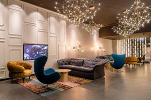 a living room with a couch and a tv and chairs at Motel One Mannheim in Mannheim