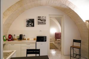 une cuisine avec une arche et des placards blancs dans l'établissement Arco Felice, à Giovinazzo