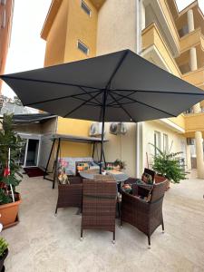 Apartments Edona في أولتسينج: مظلة سوداء كبيرة على طاولة وكراسي