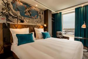 Habitación de hotel con cama grande con almohadas azules en Motel One Paris-Porte Dorée, en París