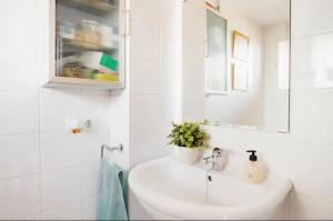 Baño blanco con lavabo y espejo en La casa de Marilo en Tomares