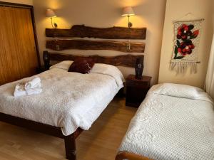 a bedroom with two beds and a wooden headboard at Hotel Sueños del Volcan in Villarrica