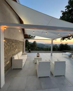 a patio with white furniture and a stone wall at Ciabot Donna Rosa in Santo Stefano Belbo