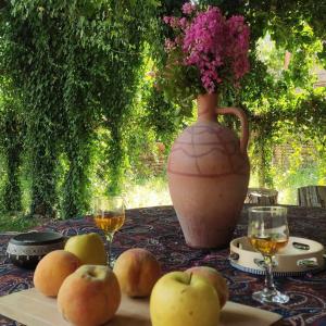 a table with a vase and apples and wine glasses at Tuta House Sighnaghi in Sighnaghi
