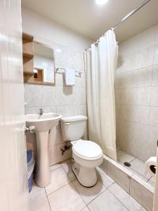 a white bathroom with a toilet and a sink at Hostal Posada Del Sol in Guayaquil