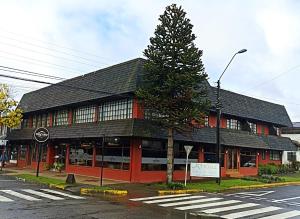un edificio rojo con un árbol delante de él en Hotel Sueños del Volcan, en Villarrica
