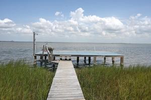 a dock on the water with a bench on it at Bay View Glamping in Bolivar Peninsula