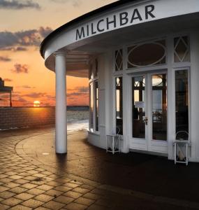 a building on the beach with the sunset in the background at Kleine Milchbar in Norderney