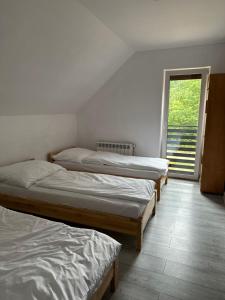 three beds in a room with a window at Domek u Pilota in Ropienka