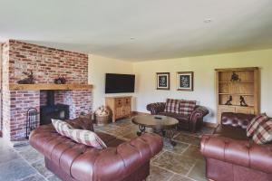 a living room with leather furniture and a fireplace at Big Barn 