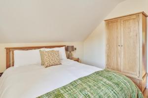 um quarto com uma cama branca e um armário de madeira em The Byre 