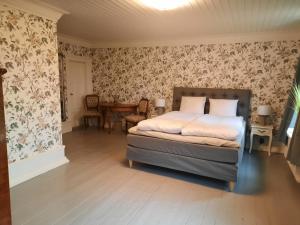 1 dormitorio con cama y papel pintado con motivos florales en Sjötorps Säteris 1600-tals Huvudbyggnad en Larv