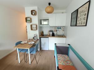 a small kitchen with a table and blue chairs at Studio Cosy neuf + lit bébé à 4 minutes RER A in Montévrain