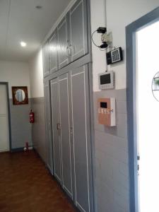 a hallway with gray lockers and a clock on the wall at Comme Chez Soi 1 in Pointe-Noire