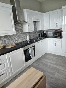 a kitchen with white cabinets and a sink at Saltwater Edge Apartment in Portrush