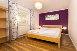 ein Schlafzimmer mit einem Bett und einer lila Wand in der Unterkunft Appartement Am Tatscherlehen in Piesendorf