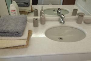 - un lavabo blanc dans la salle de bains avec des serviettes dans l'établissement Seveso Centro stazione , 15 minuti da Milano, à Seveso