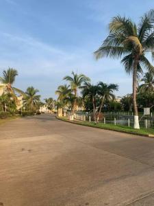 an empty street with palm trees and a fence at Depto con PISCINA PUENTE DEL MAR ACAPULCO in Acapulco